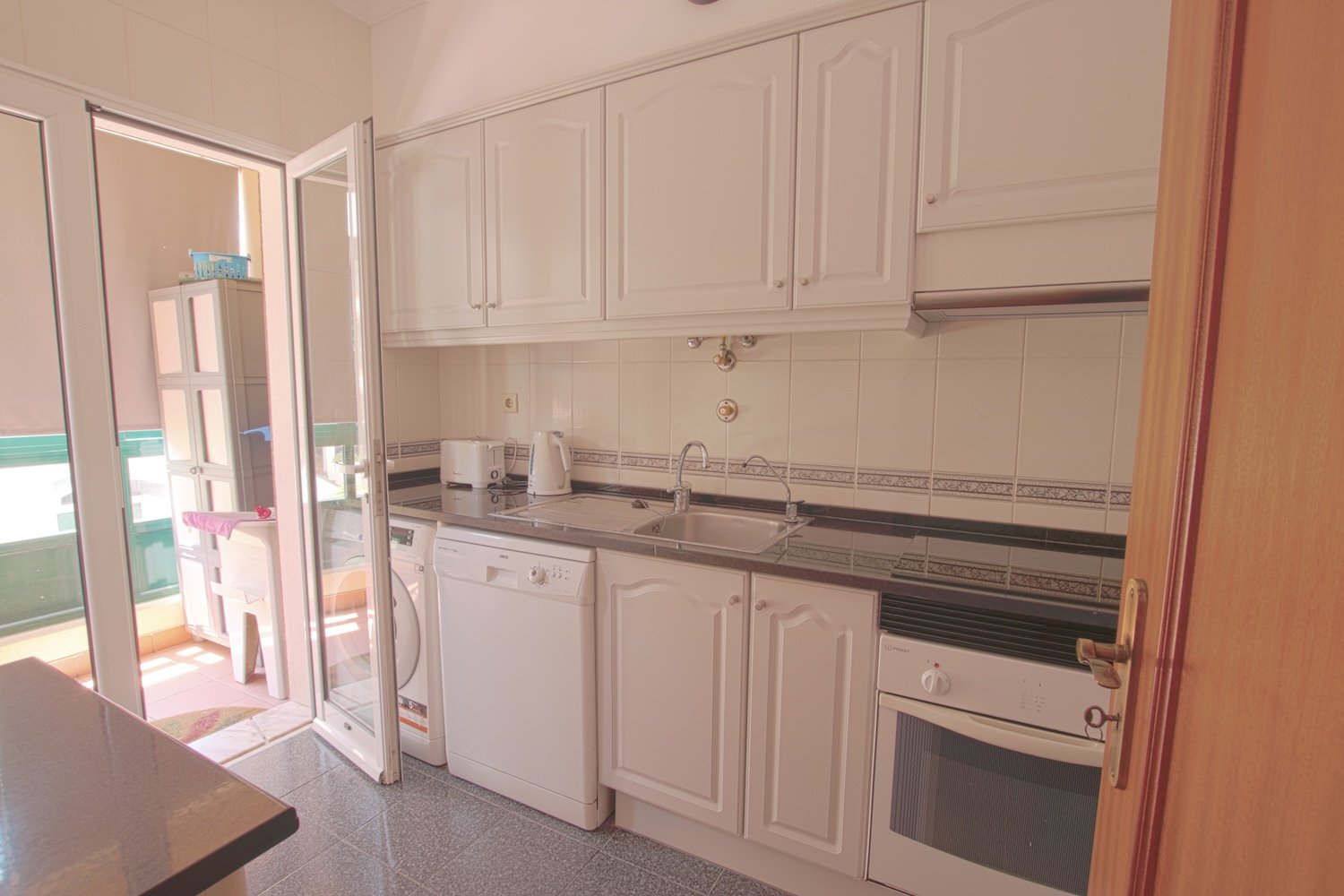 A view of the kitchen including a sink, an oven, a stove, a washing machine and a dishwasher
