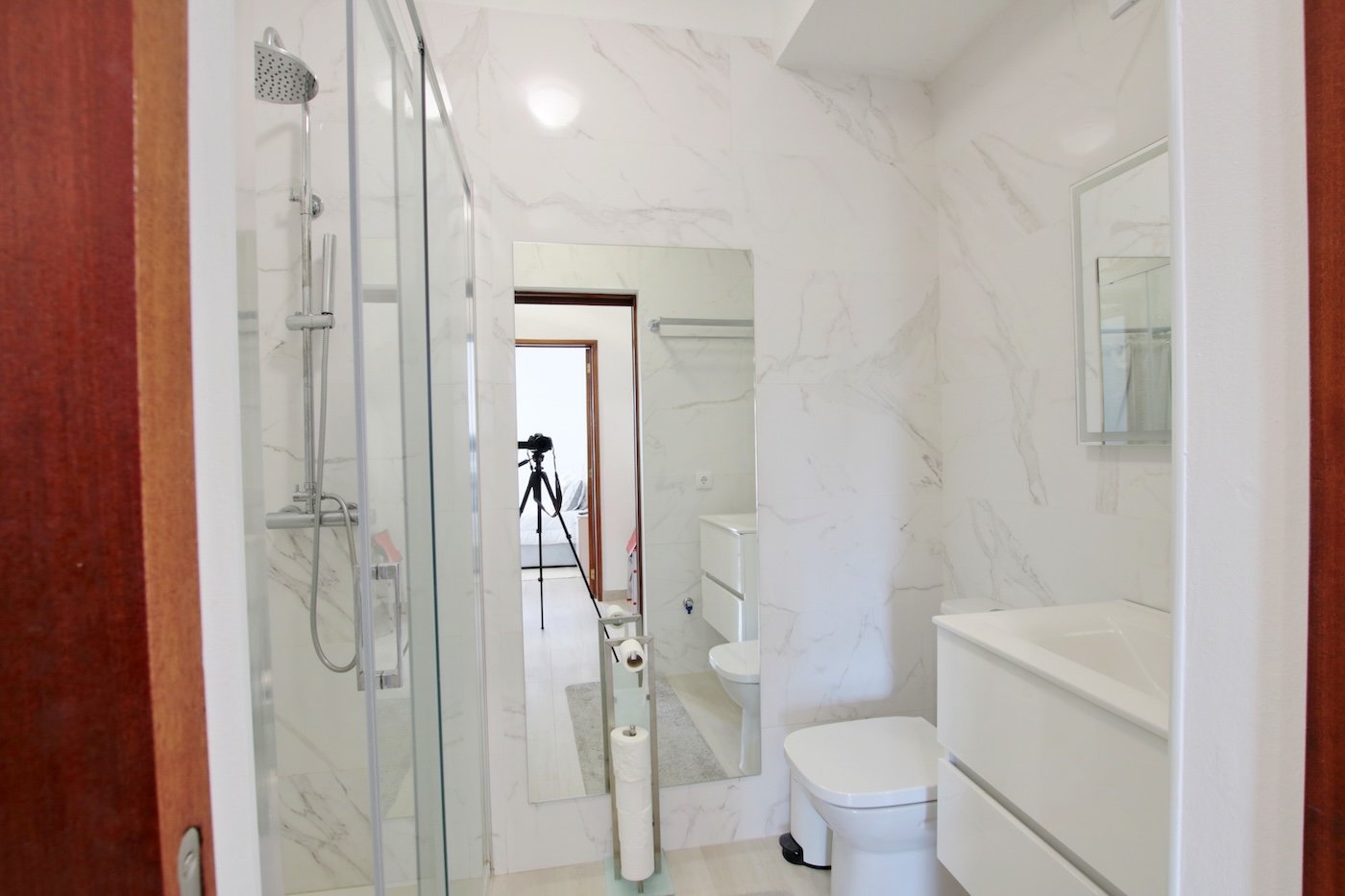 Bathroom with shower, hand basin, toilet seat and two mirrors