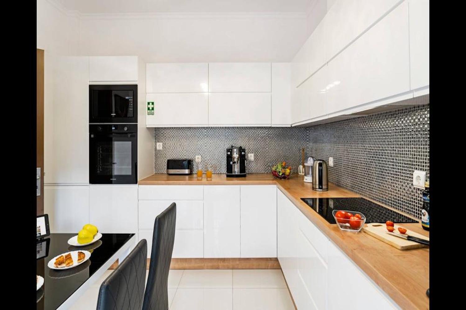Kitchen area with white cupboards, a table and chairs