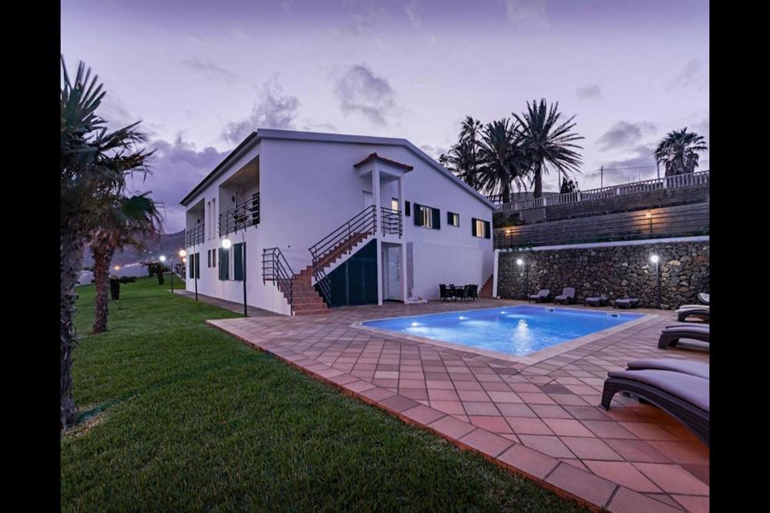 Side facade of the house and its swimming pool in the evening