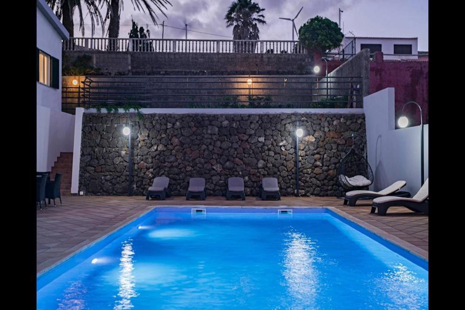 Swimming pool area in the evening showing the pool and sunloungers
