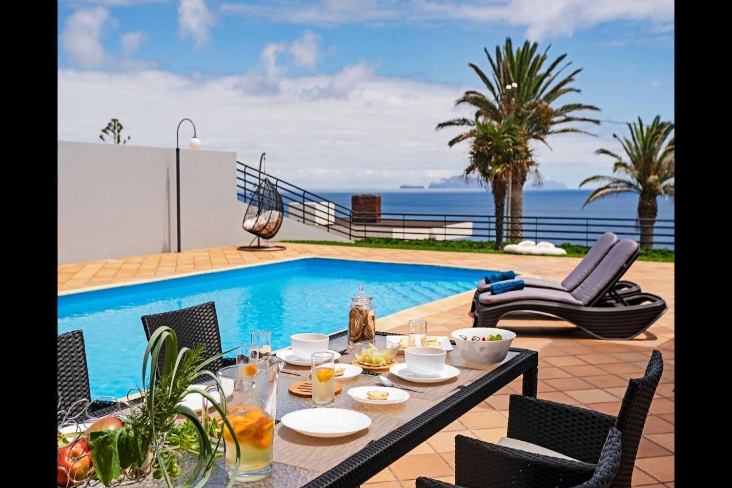 Swimming pool area with a table, some chairs and some sunloungers