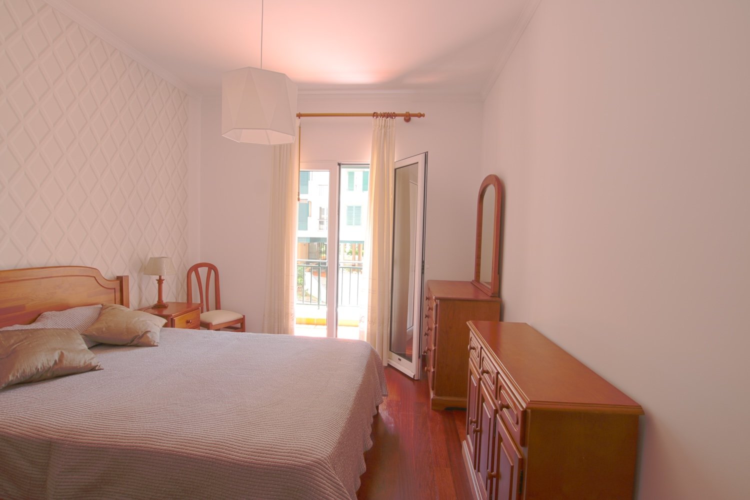 The bedroom with a double bed, a three-drawer nightstand, a chair, 2 sideboards (one with a mirror) and access to the secondary veranda