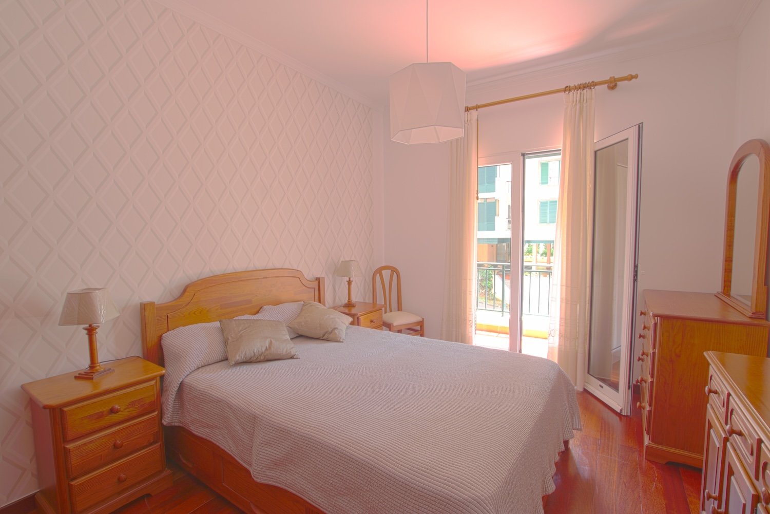 The bedroom with a double bed, two three-drawer nightstands, 2 sideboards (one with a mirror) and a chair