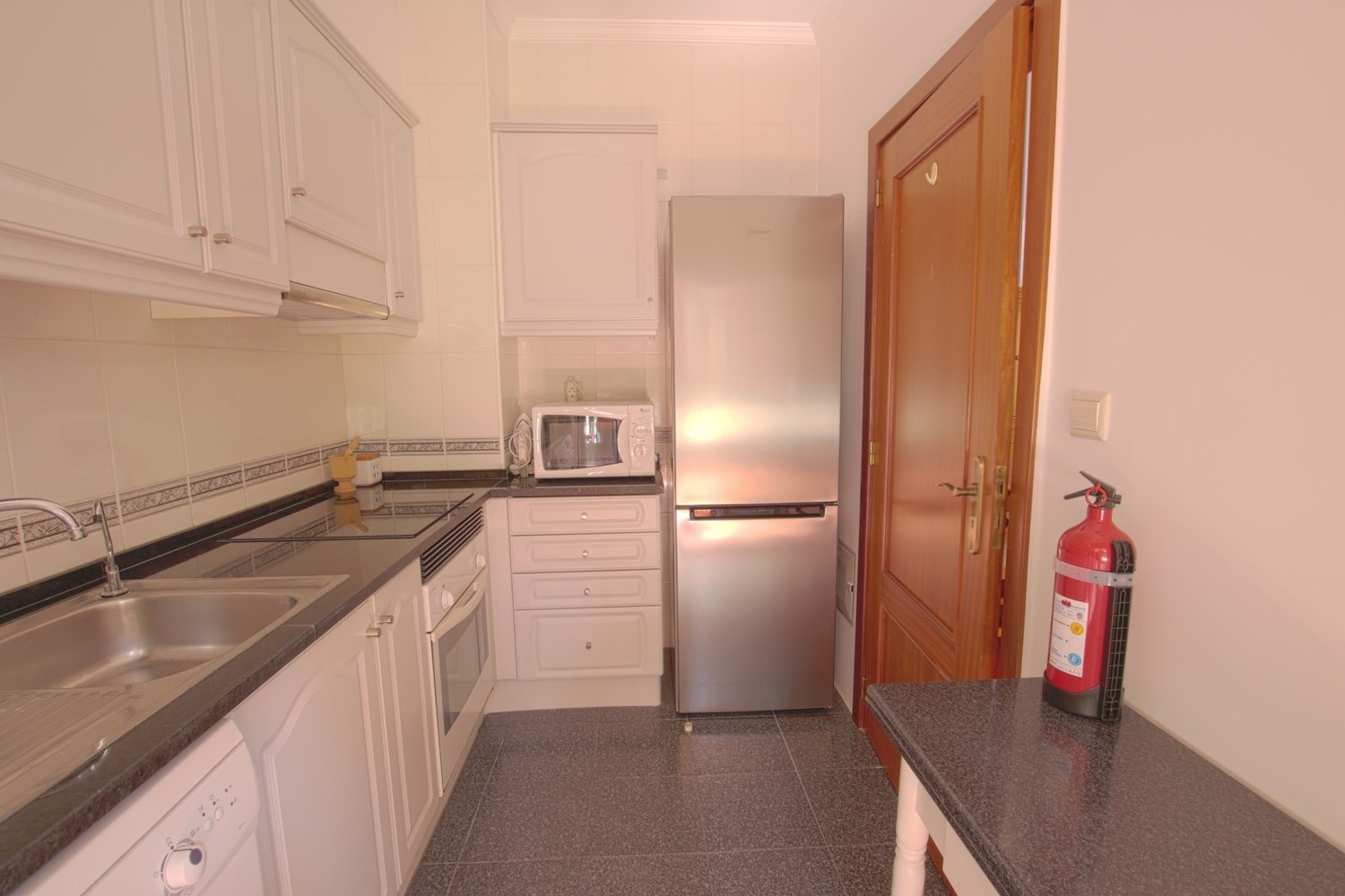 The kitchen with a sink, a fridge the dishwasher and the oven