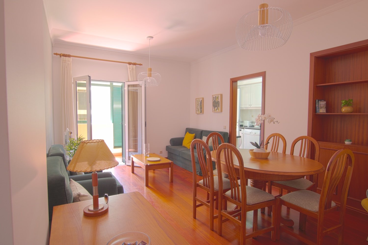 The living room showing the dining table, its chairs, two armchairs, a sofa and the entrance to the kitchen