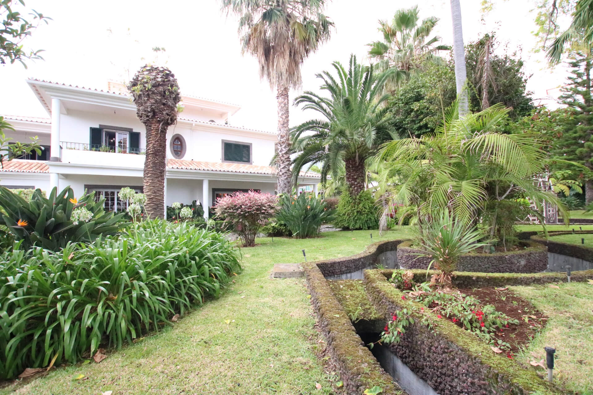 Garden with trees and greenery and the side of the manor home